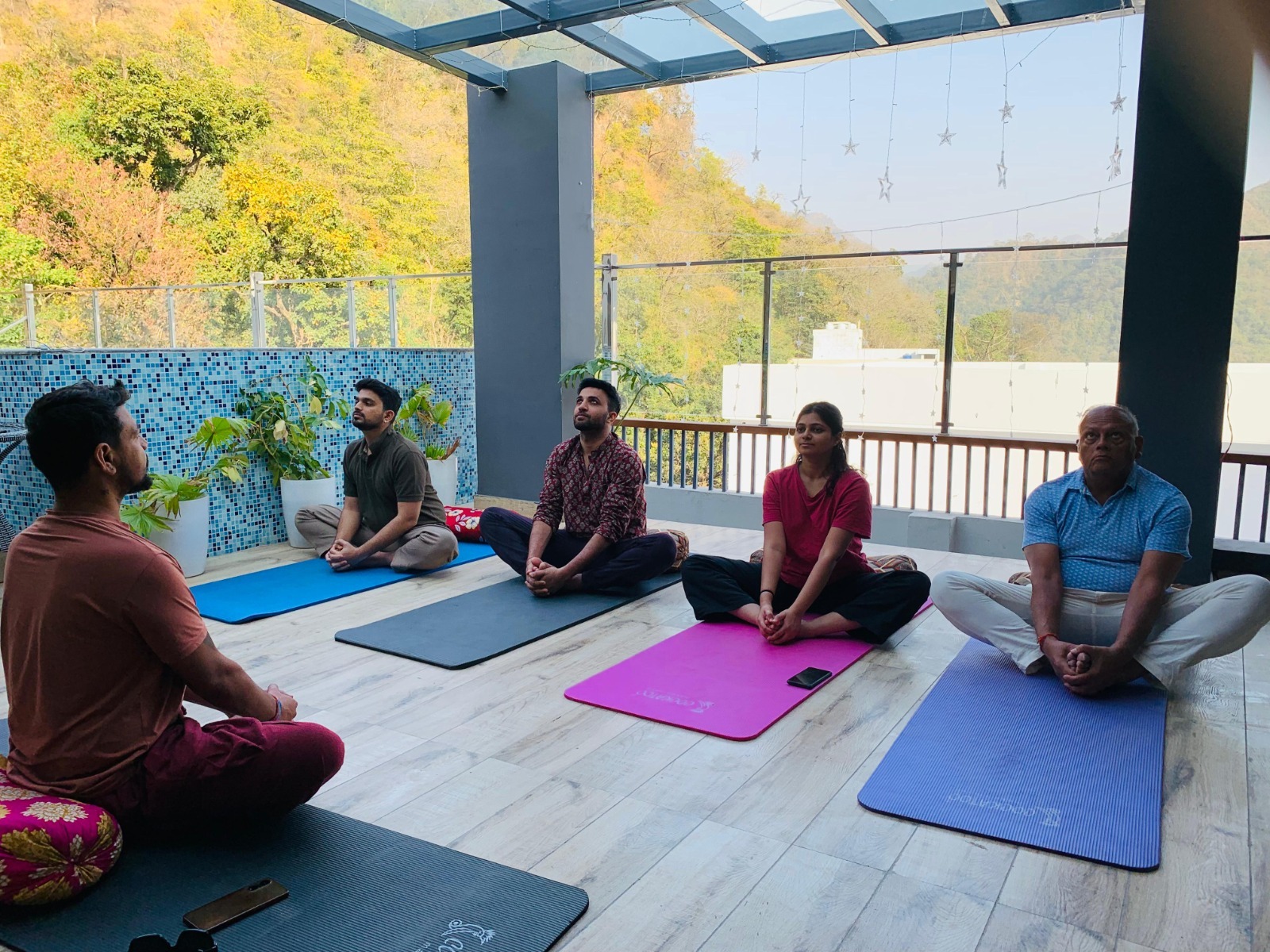 A small group practising meditation on a mountain terrace